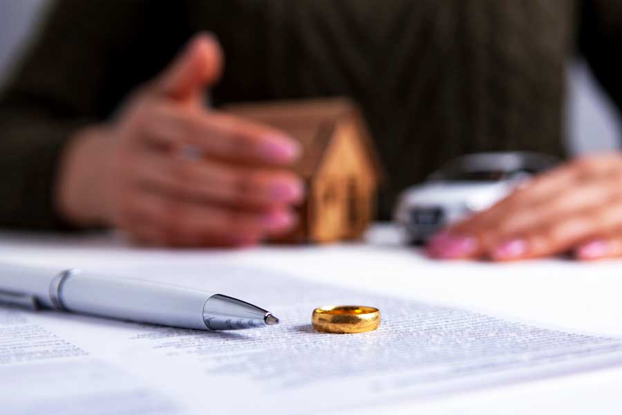 Woman's hands with divorce papers, pen, and ring - division of property concept