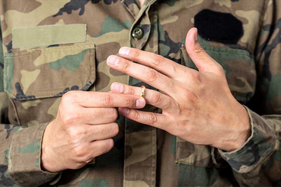Close up of hands of a man in the military removing his wedding ring