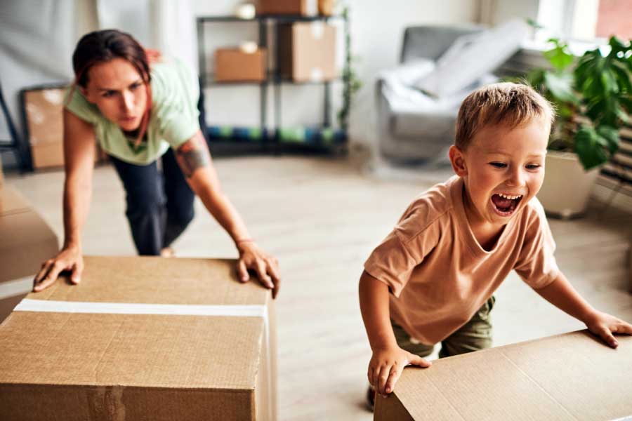 Mother and cheerful young son pack boxes during a move