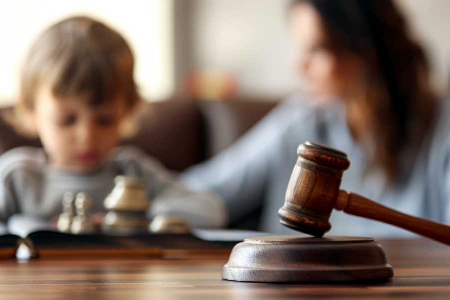 Close-up of a judge's gavel with a blurred mother and child in the background