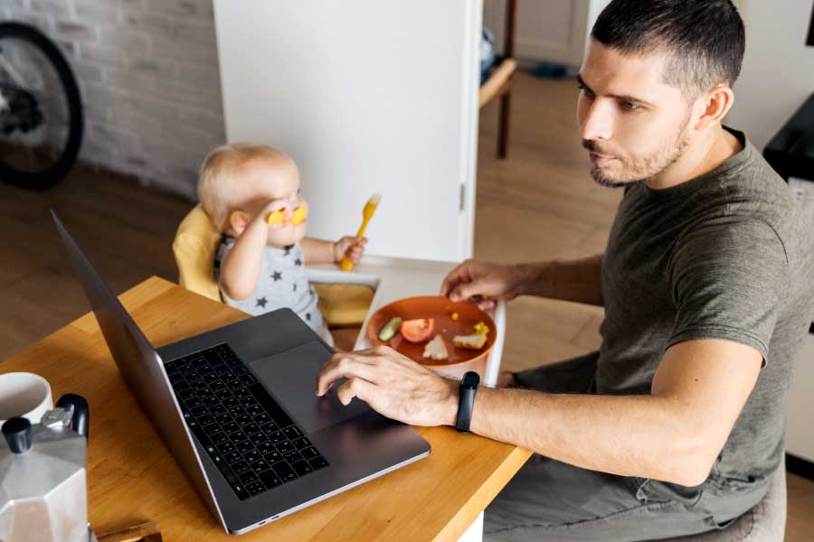 Father works remotely while caring for a small child