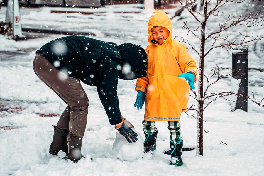 Parent and child building a snowman