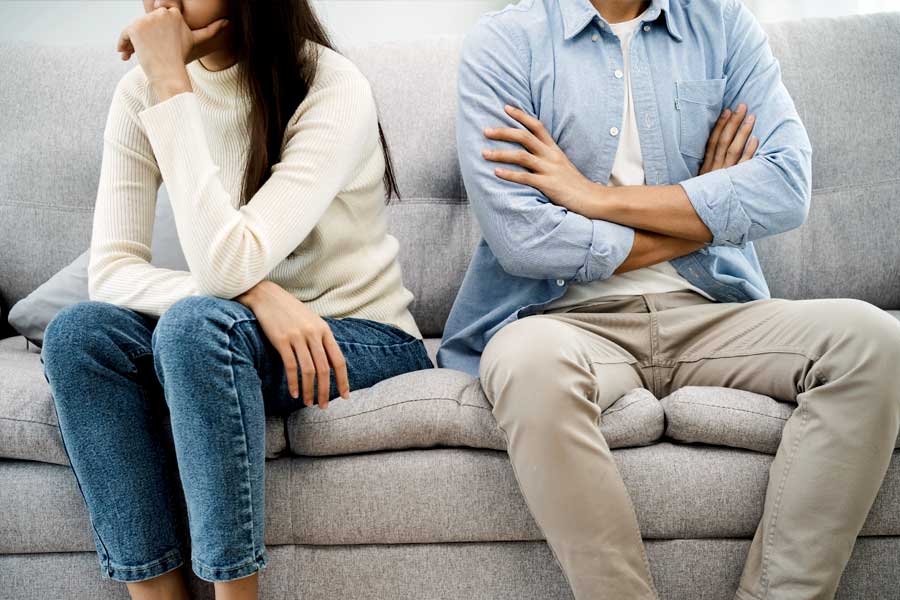 Man and woman sitting separately on a couch after quarrel at home.