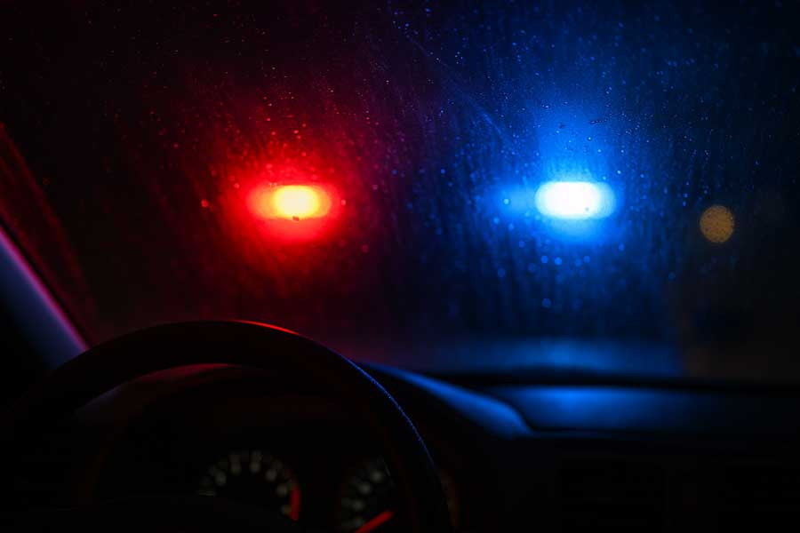 Police lights flash through a car windshield during a DUI stop
