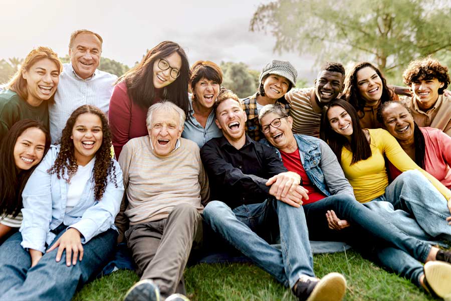 Multigenerational family sitting on grass in a public park
